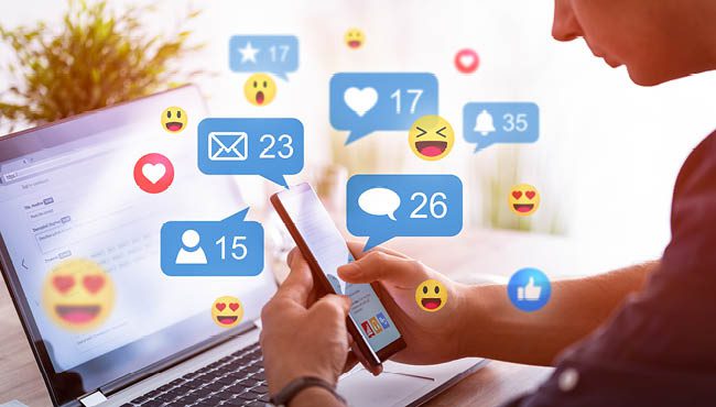 Un gestionnaire de communauté utilisant un ordinateur portable avec des émoticônes représentant les interactions sociales.