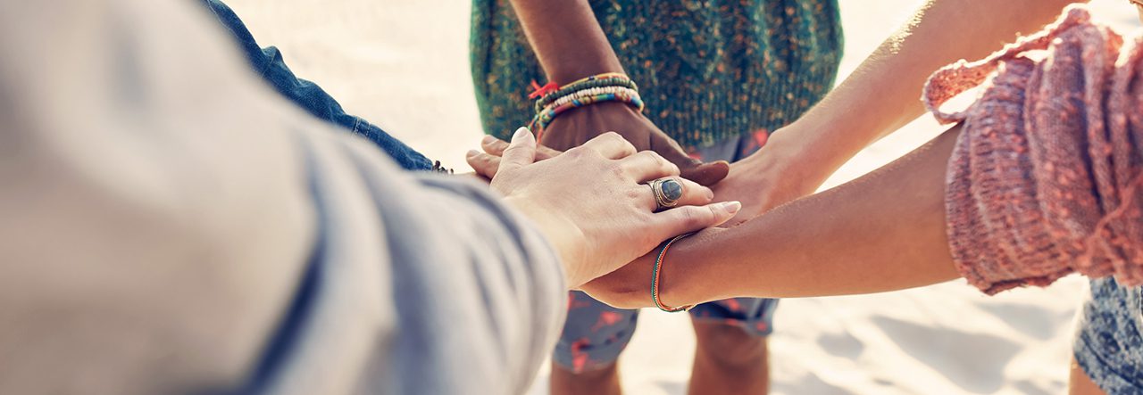 Un groupe de personnes se tenant la main sur la plage, incarnant le sentiment d’appartenance à une communauté locale et soulignant l’importance de la transition numérique et d’une formation optimisée.